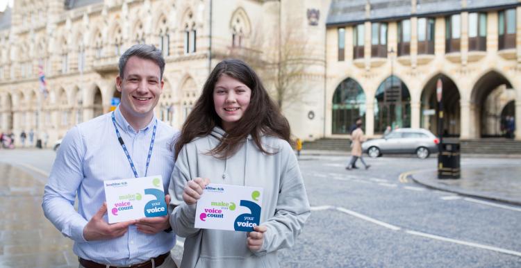 Young adult male volunteer with young female volunteer holding promotional material