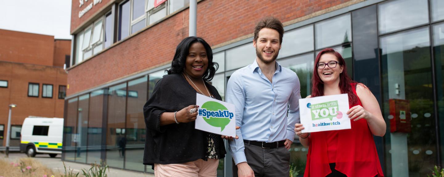 Group of Healthwatch volunteers outside a hospital holding 'Speak up' sign