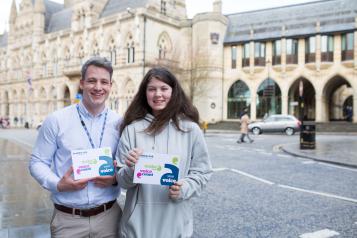 Young adult male volunteer with young female volunteer holding promotional material